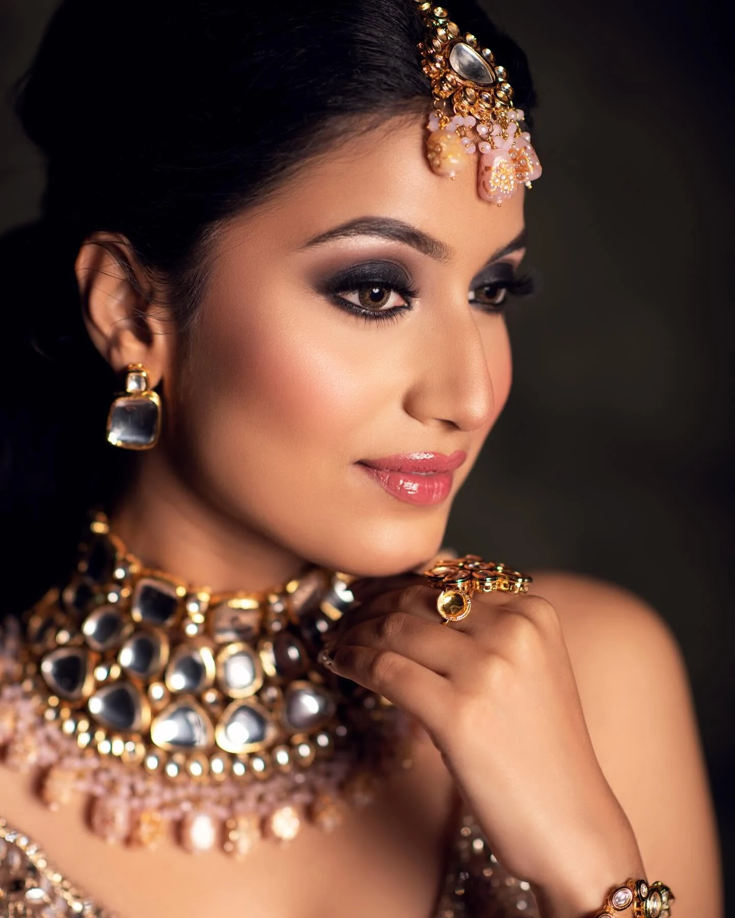 Close-up portrait showing smoky eye makeup, a glossy lip and statement jewellery.